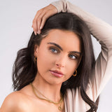 Model wearing ARIIRA Nina Layered Circle Charm Necklace, featuring gold chains and a polished circle charm.