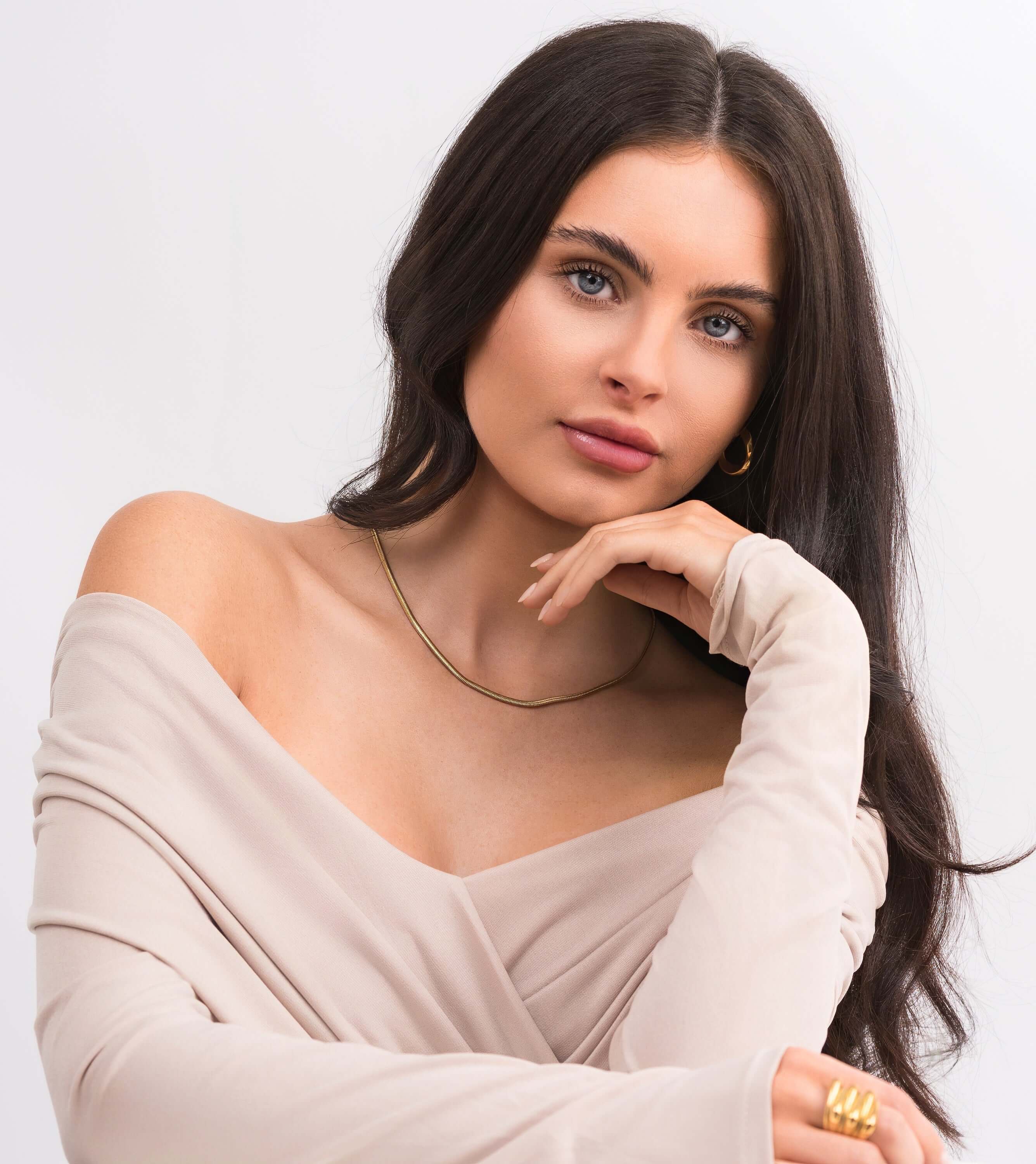Model showcasing the Alina Gold Herringbone Necklace, exuding elegance with a silky soft finish in natural lighting.