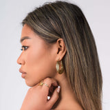 Model wearing Elia Sculpted Oval Hoop Earrings showcasing their reflective finish and lightweight design.