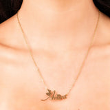 Gold Amira custom name necklace featuring flowing script and heart details, worn elegantly on a model's neck.