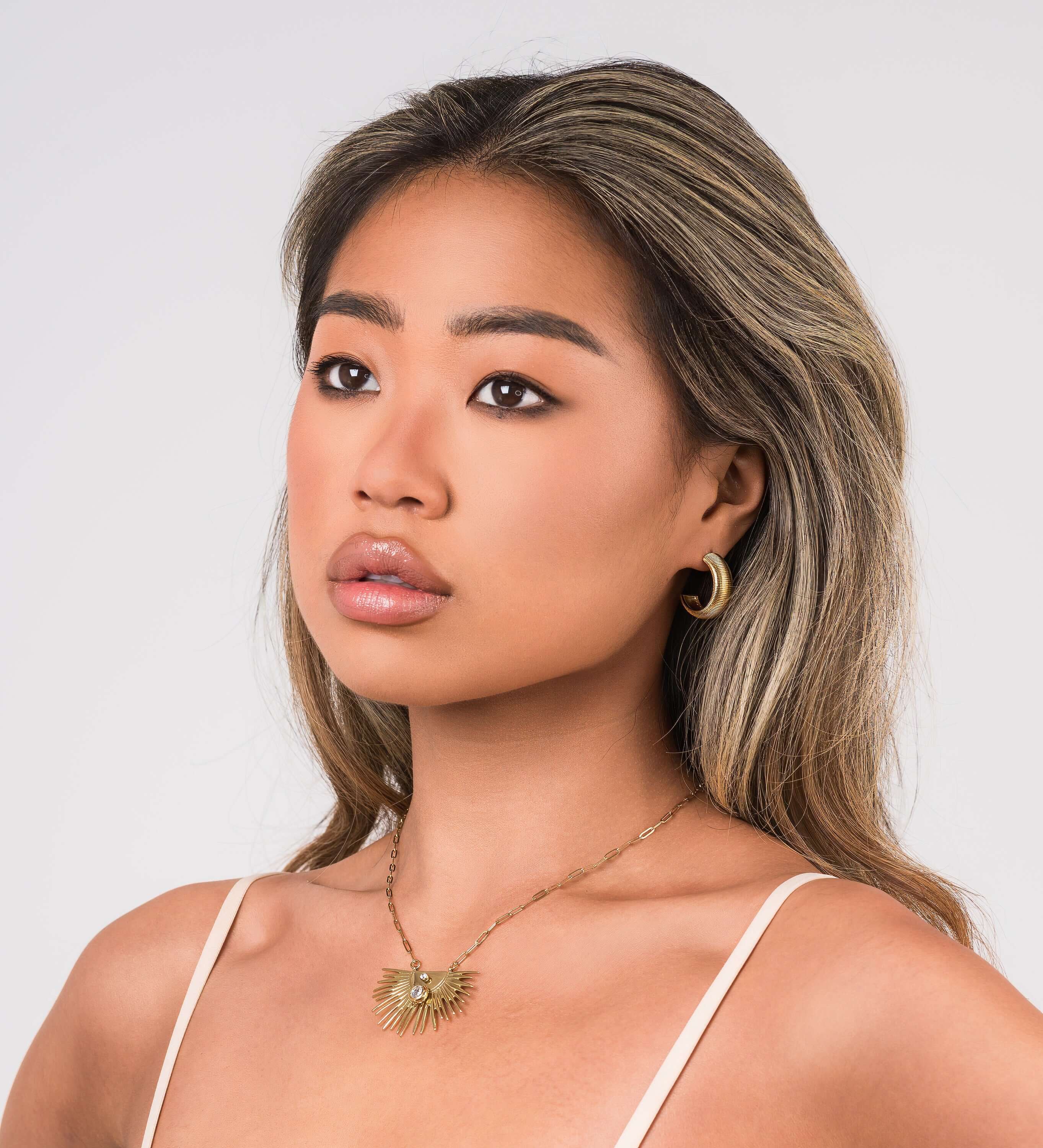 Elara Radiant Sunburst Pendant Necklace worn by a model, showcasing crystal detail and radiant spikes.