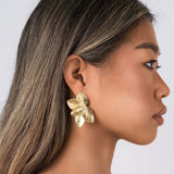 Flora Textured Bloom Stud Earrings by ARIIRA, showcasing a model wearing elegant gold floral studs.