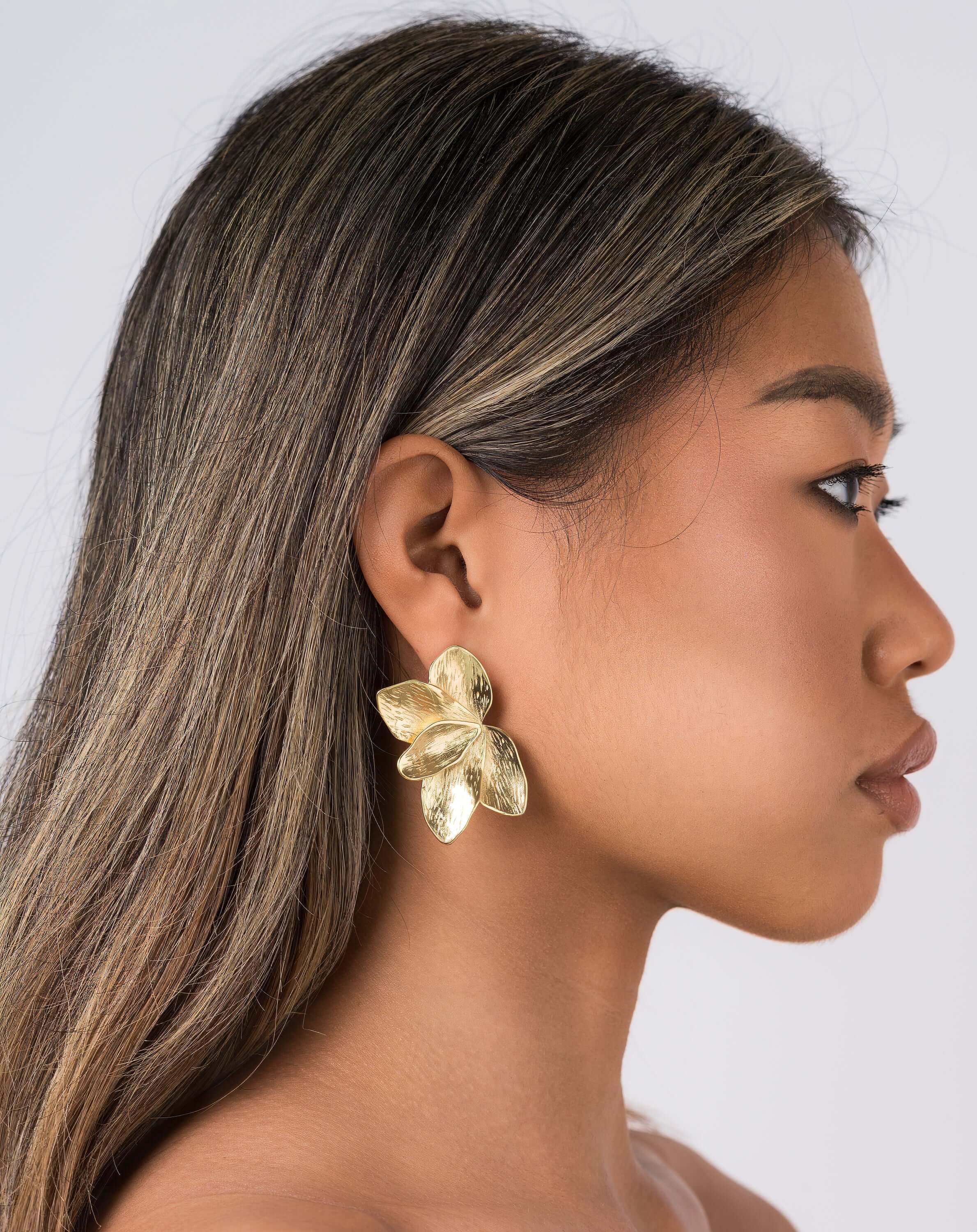 Flora Textured Bloom Stud Earrings by ARIIRA, showcasing a model wearing elegant gold floral studs.