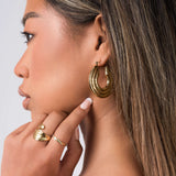 Woman wearing ARIIRA Elia Sculpted Oval Hoop Earrings, showcasing their fluid shape and reflective finish.