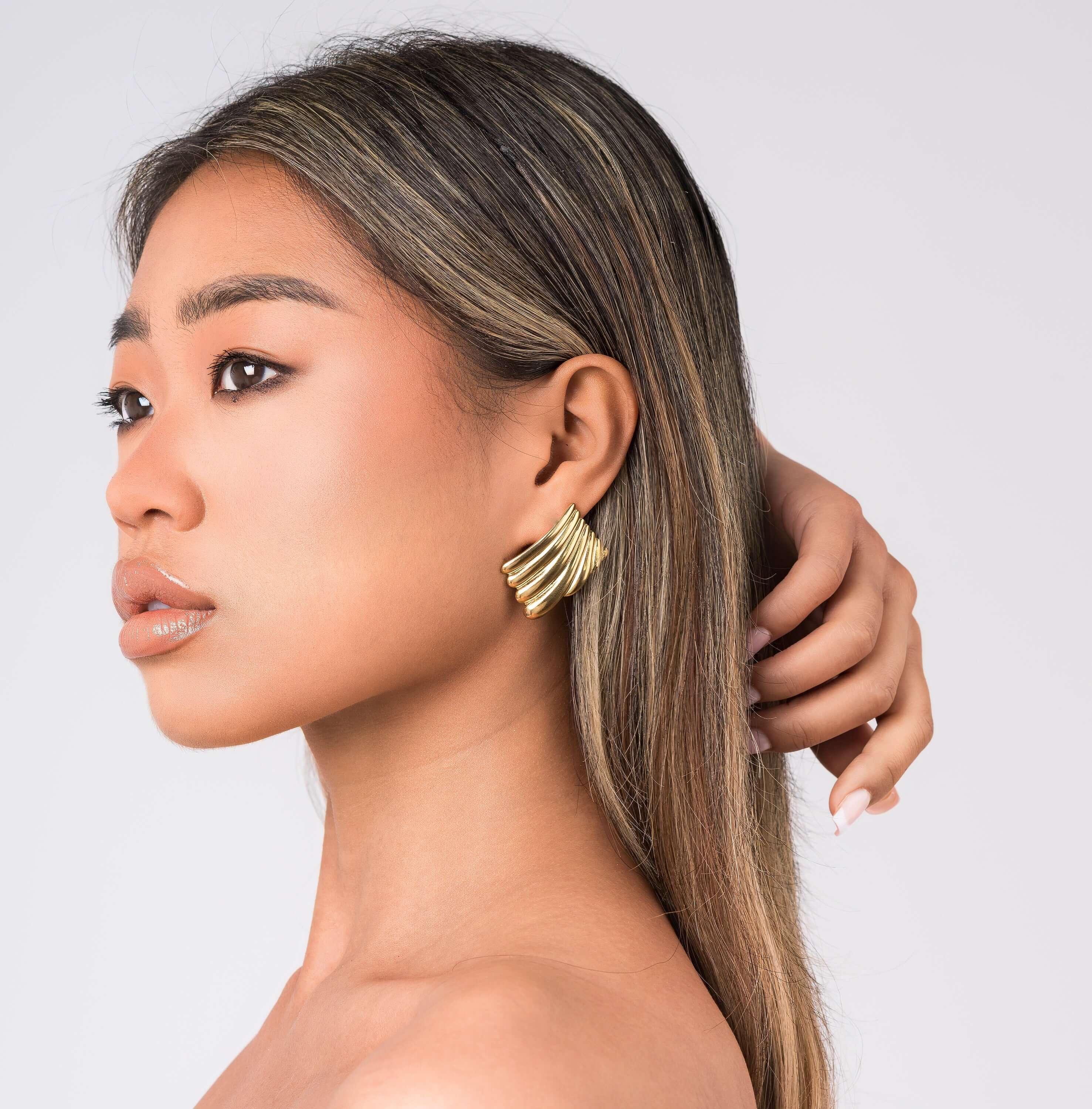 Model wearing ARIIRA Freya Sculpted Wave Hoops, showcasing their elegant ridged gold design.