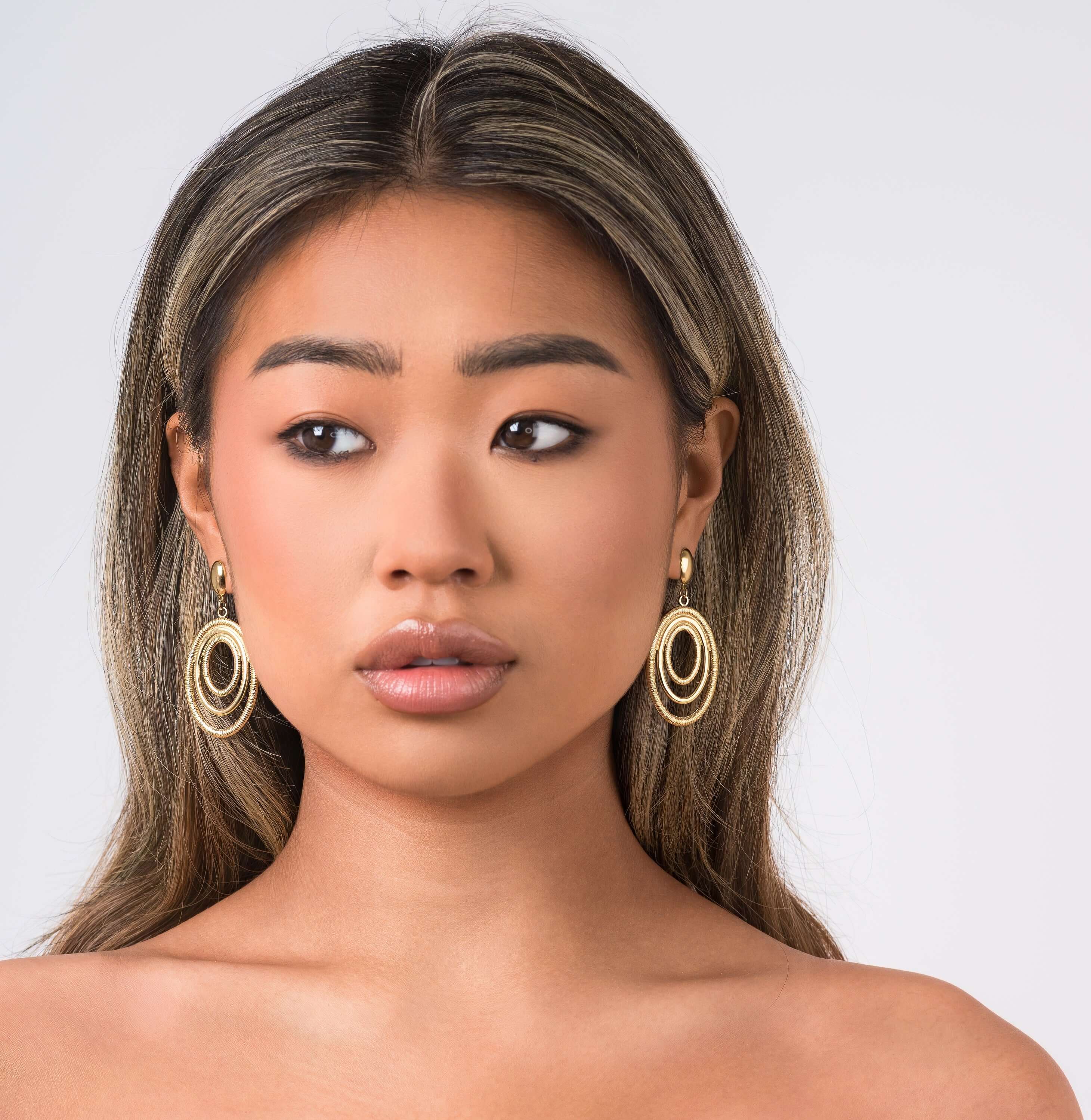 Elegant Elena Orbit Drop Earrings by ARIIRA featuring sculptural golden curves and a modern design.