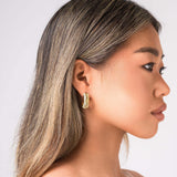 Profile view of a model wearing ARIIRA Selene Ribbed Hoop Earrings, showcasing their gold ribbed design and polished finish.
