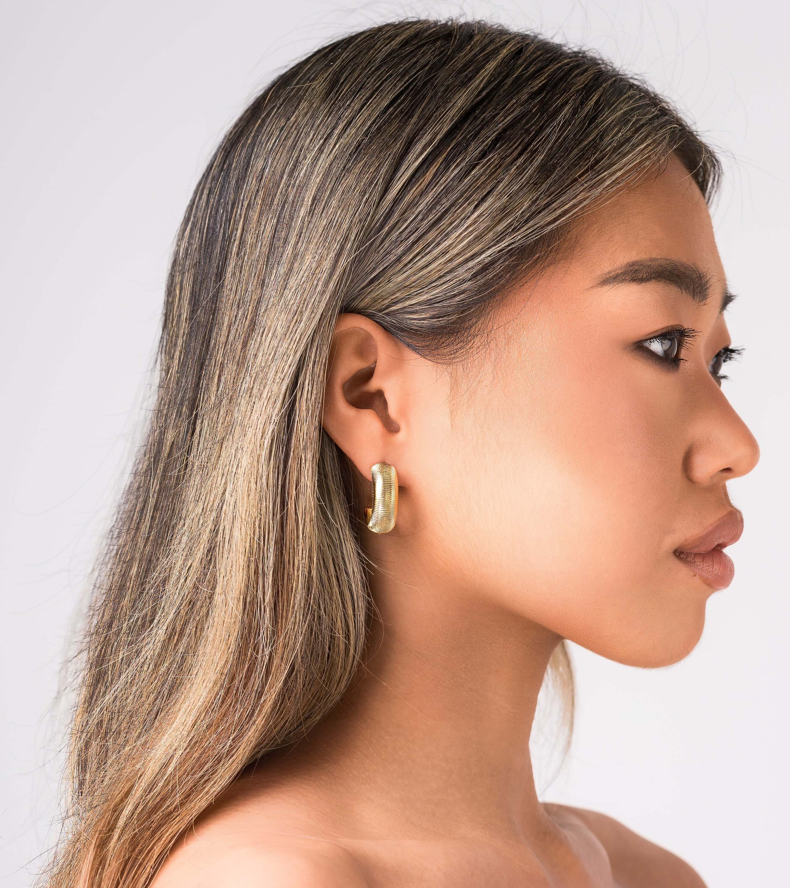 Profile view of a model wearing ARIIRA Selene Ribbed Hoop Earrings, showcasing their gold ribbed design and polished finish.