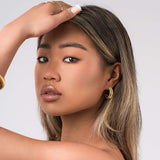Young woman showcasing Selene Ribbed Hoop Earrings, featuring fine ridged detailing and a polished brushed finish.