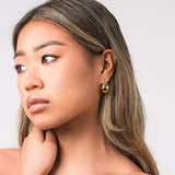 Ziva chunky gold hoop earrings worn by a model, showcasing their sculptural design and polished finish.