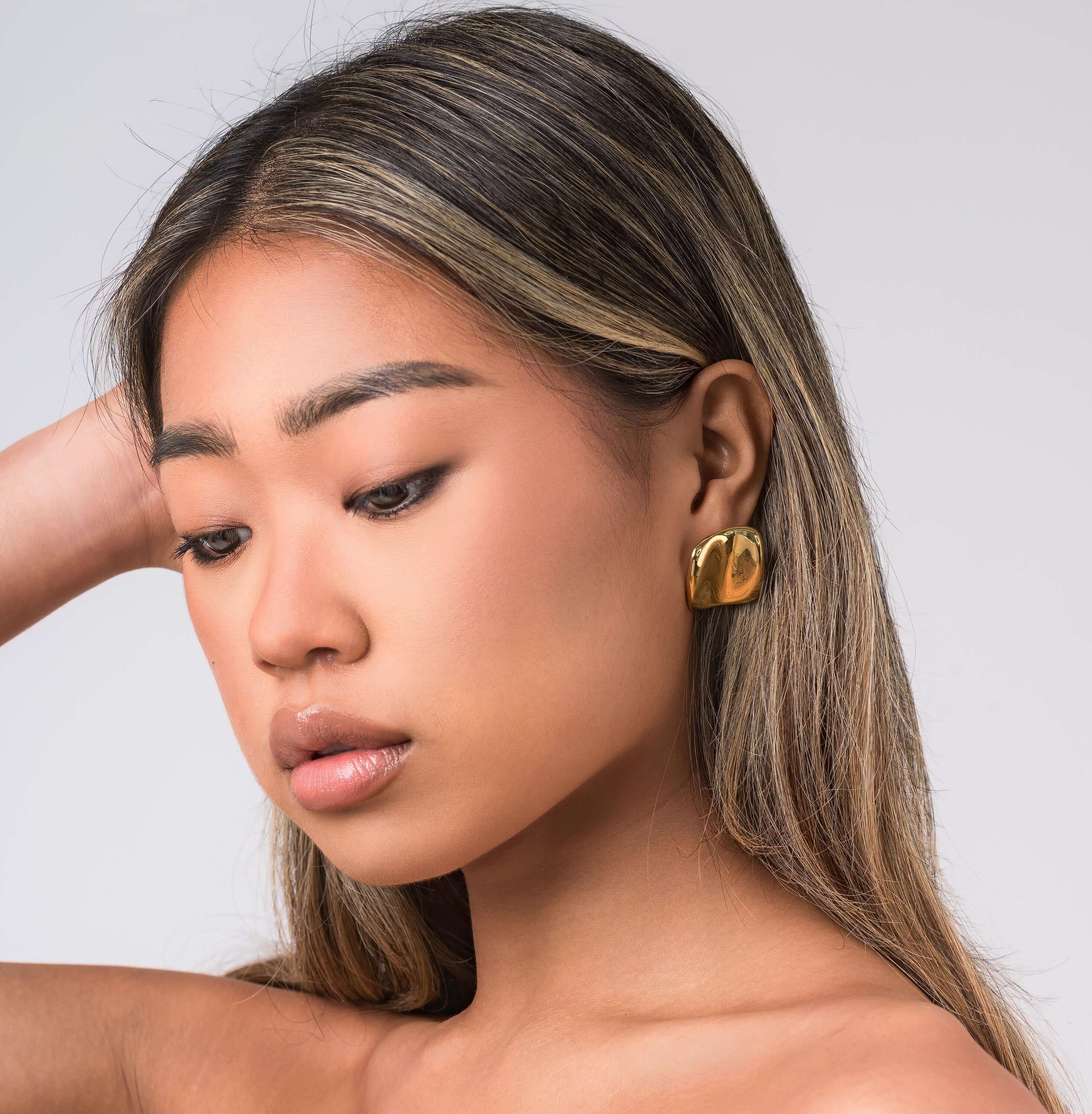 Close-up of a woman wearing ARIIRA Lara Organic Drop Studs earrings, showcasing their modern design and polished glow.