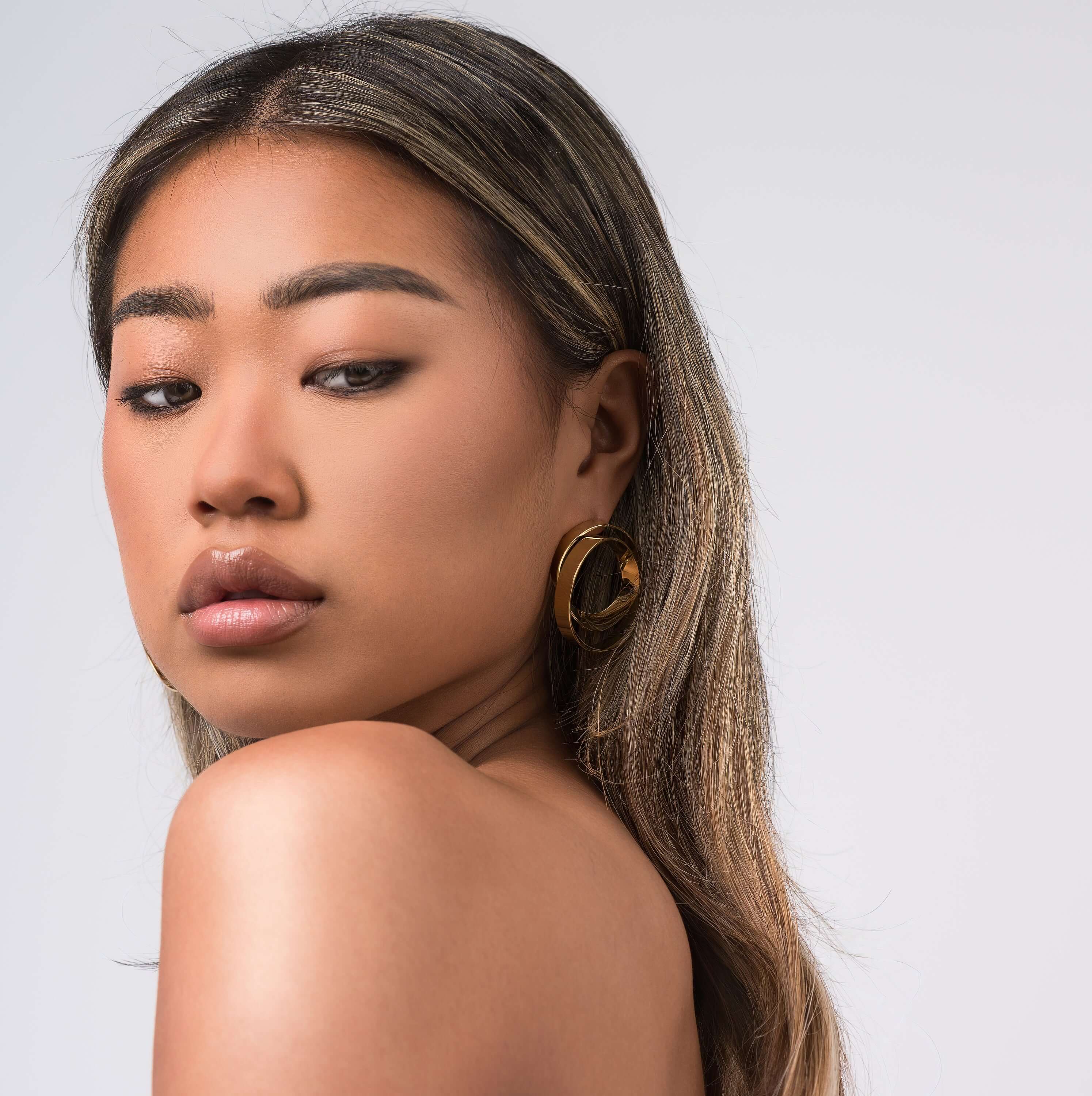 Woman wearing ARIIRA Noor Double Hoop Statement Earrings, showcasing a modern and elegant look with a light and polished design.