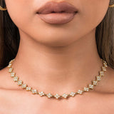 Delicate ARIIRA Lina Crystal Flower Link Necklace featuring gold links shaped like blossoms, adorned with shimmering crystals.