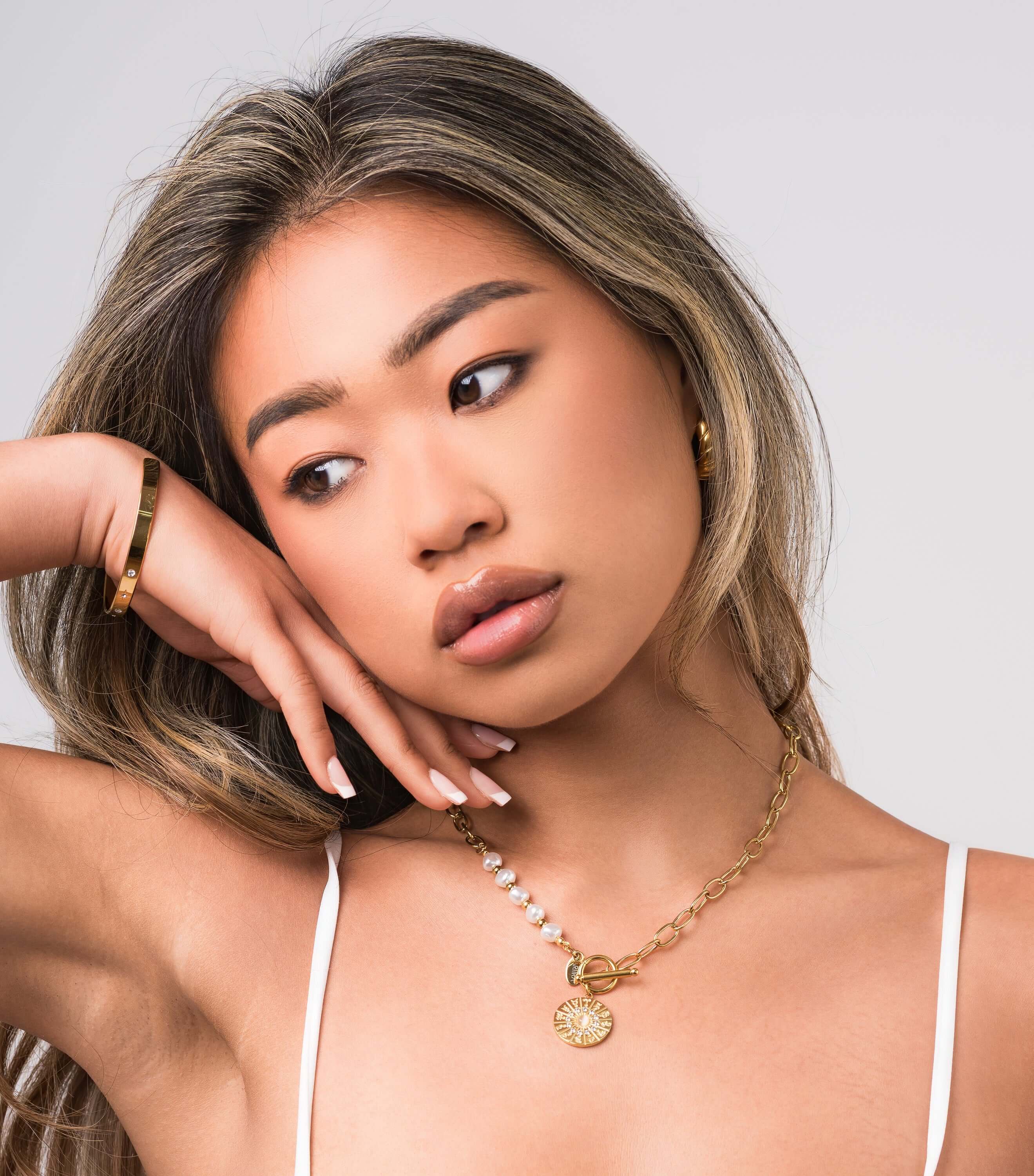 Model showcasing the ARIIRA Mira Pearl Link Medallion Necklace with freshwater pearls and gold chain links.