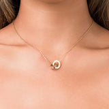 Close-up of ARIIRA Reina Roman Circle Pendant Necklace featuring a polished circle and crystal charm.