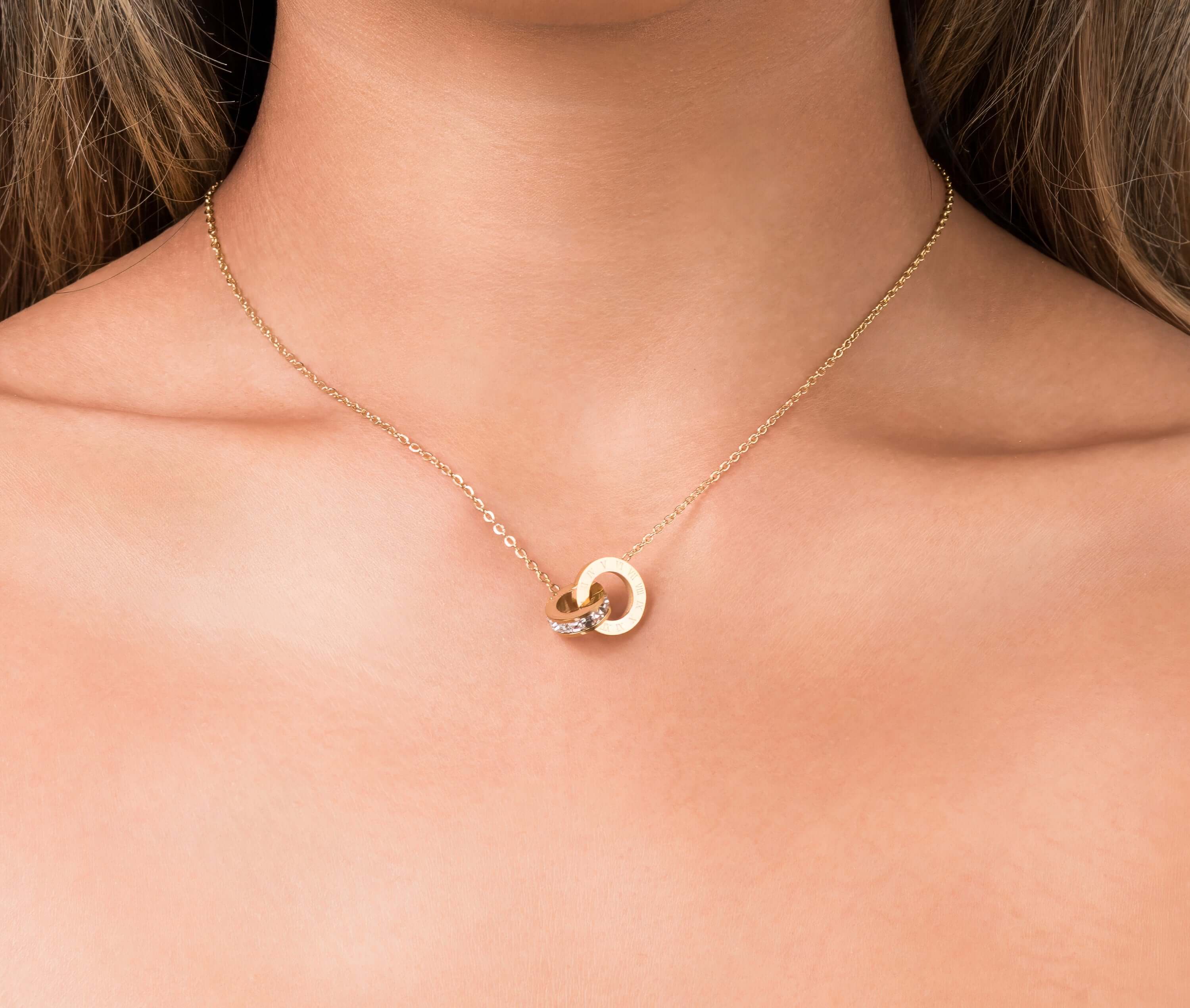 Close-up of ARIIRA Reina Roman Circle Pendant Necklace featuring a polished circle and crystal charm.