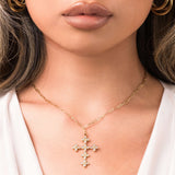 Close-up of a woman wearing the ARIIRA Crystal Cross Pendant Necklace with shimmering stones on a gold chain.