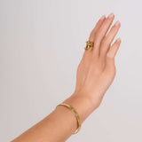 Hand wearing ARIIRA Samira Star-Set Slim Open Gold Bangle and matching ring, showcasing elegant jewelry.