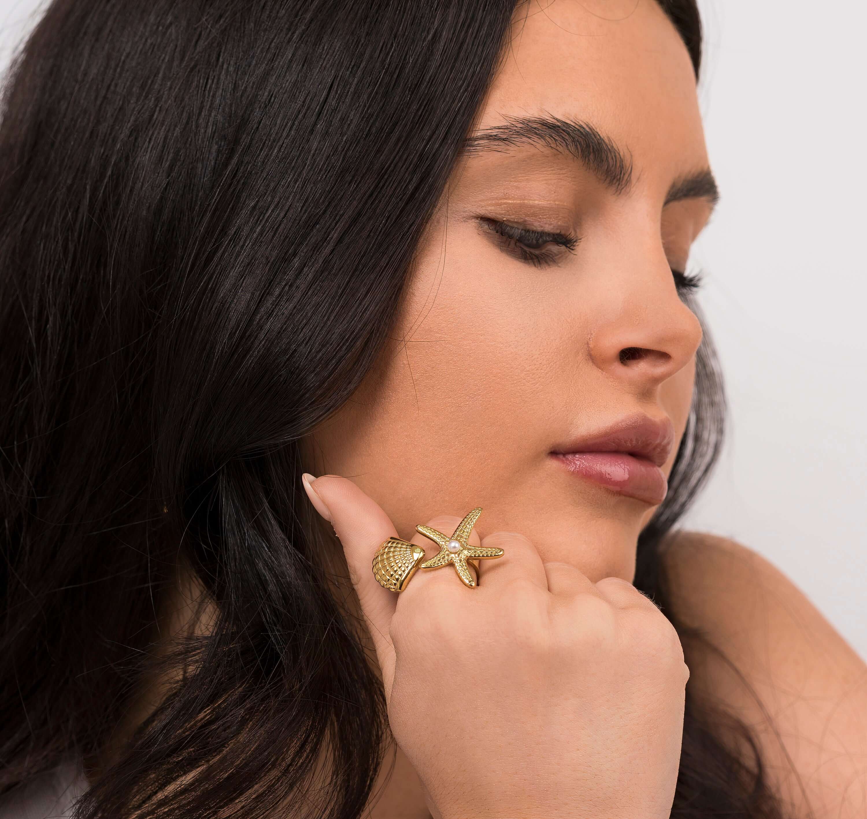Woman wearing ARIIRA Mira Starfish and Shell Pearl Ring, featuring intricate ocean-inspired design.