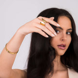 A woman showcasing the Elena Sculpted Leaf Statement Ring by ARIIRA, highlighting its elegant design and shine.