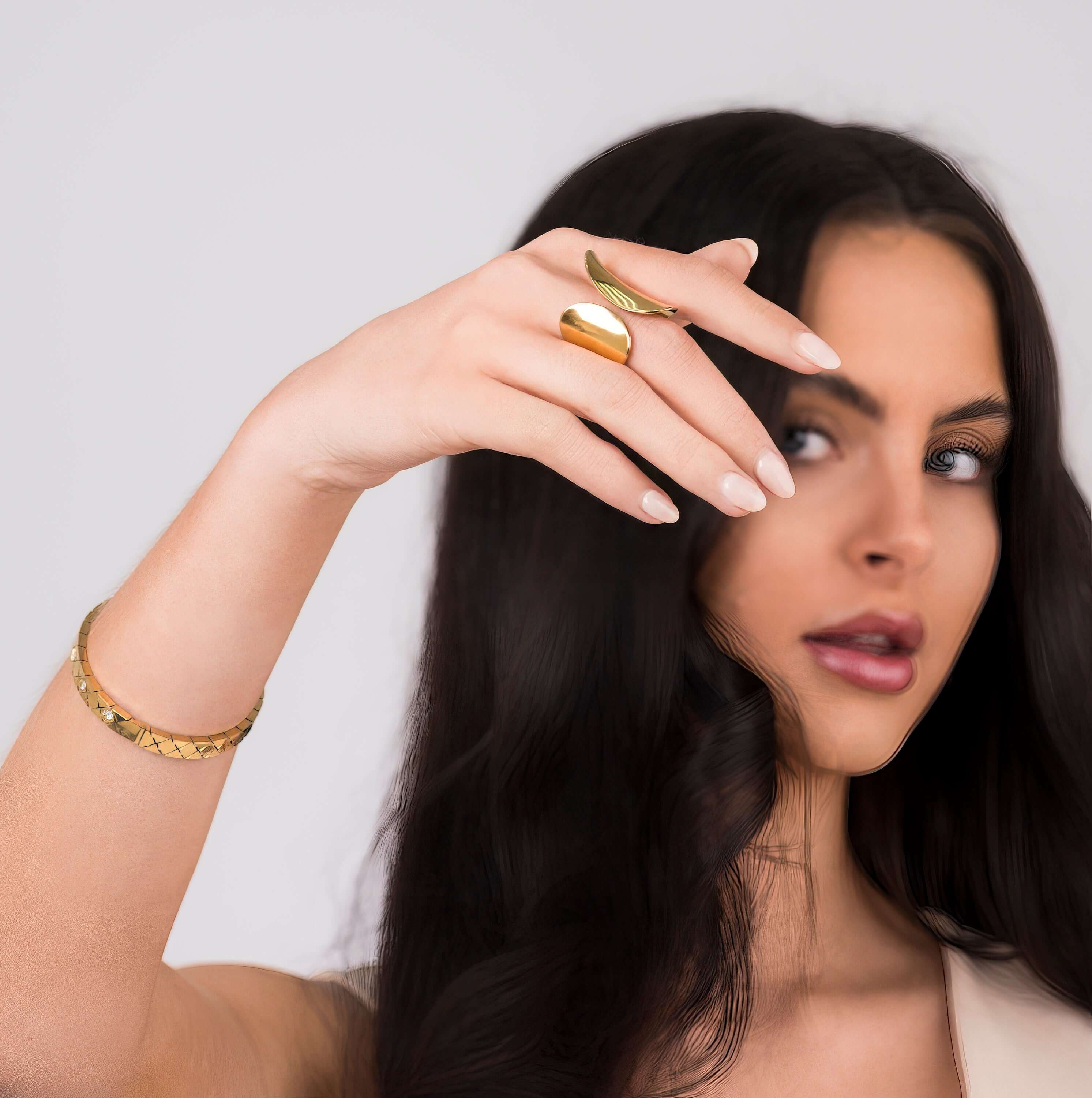 A woman showcasing the Elena Sculpted Leaf Statement Ring by ARIIRA, highlighting its elegant design and shine.