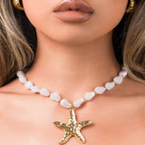 Eden Pearl Bead Necklace by ARIIRA featuring a hammered gold starfish pendant on a model.