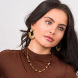 Model wearing Andrea Sculpted Teardrop Link Gold Necklace and bold gold earrings, showcasing elegant and fluid jewelry design.