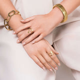 Elegant hands showcasing gold jewelry, including a geometric link chain bracelet and various rings.