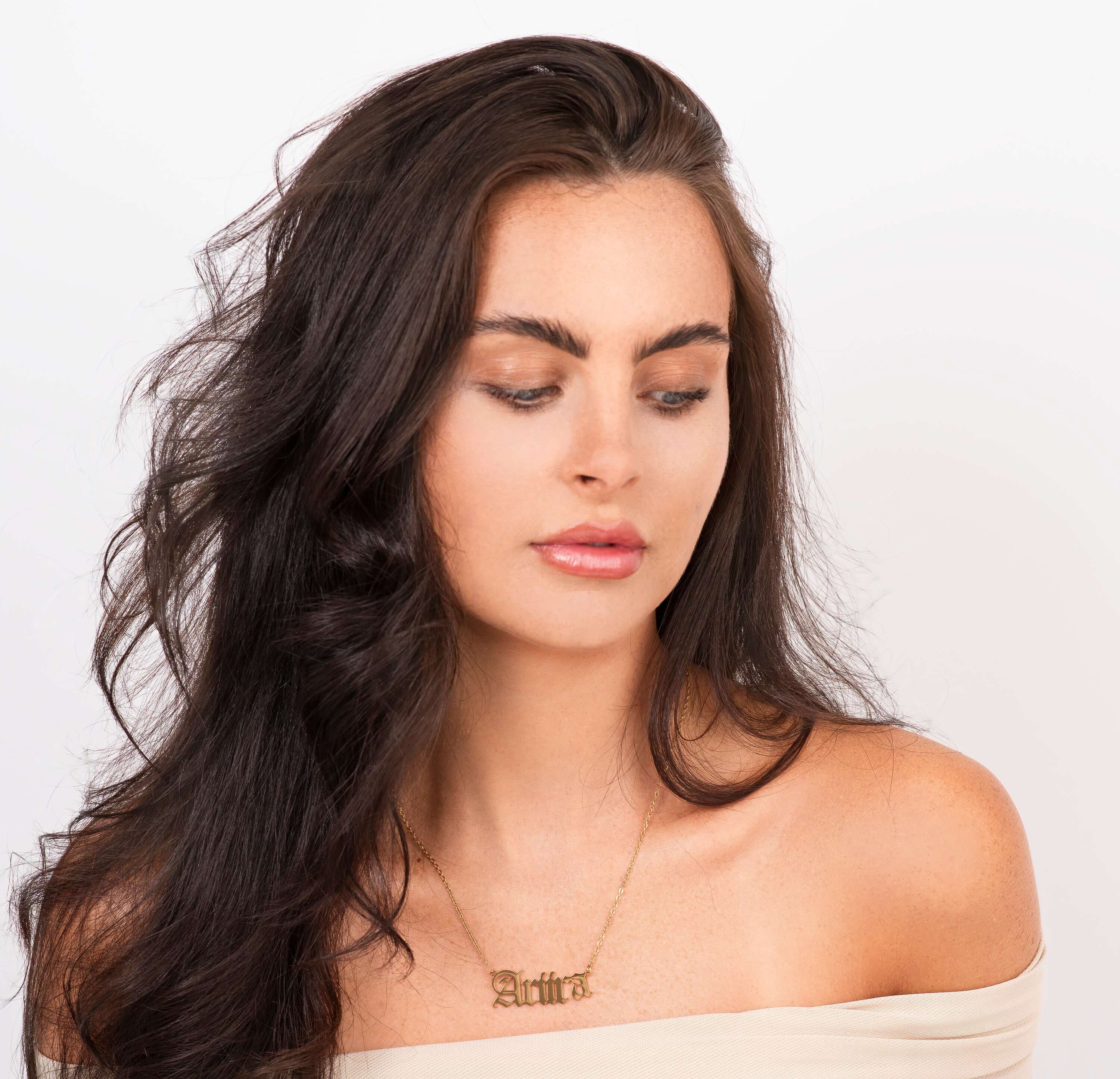 Ayla Custom Name Necklace in gold, featuring the name 'ARIIRA' worn by a model with flowing hair.