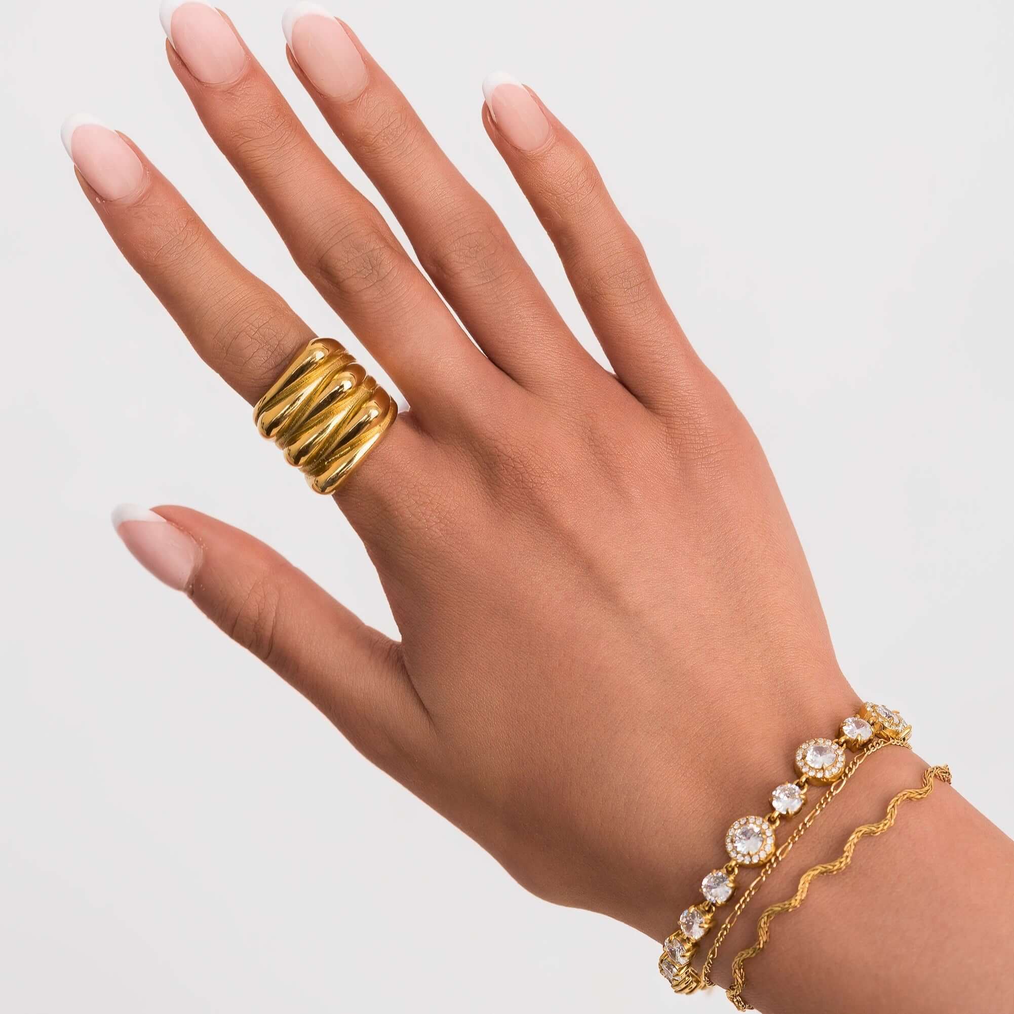 Close-up of a hand wearing a gold ring and an Amira Gold Diamante Tennis Bracelet with sparkling stones.