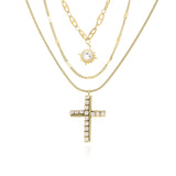Nour Layered Sun & Cross Necklace Set by ARIIRA featuring gold chains, sunburst charm, and pavé-set cross.