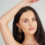 Close-up of a model wearing gold-plated Camille Crystal Bloom Earrings featuring floral design and crystals.
