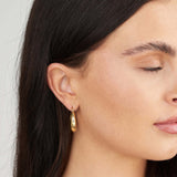 Close-up of a woman wearing ARIIRA Alina Chunky Gold Hoop Earrings, showcasing their elegant design and polished gold finish.