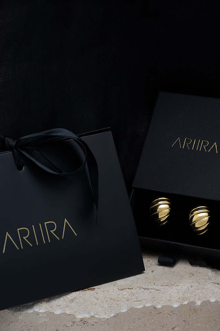 Elegant ARIIA jewelry gift box with glossy black packaging and gold accents, showcasing beautiful earrings inside.