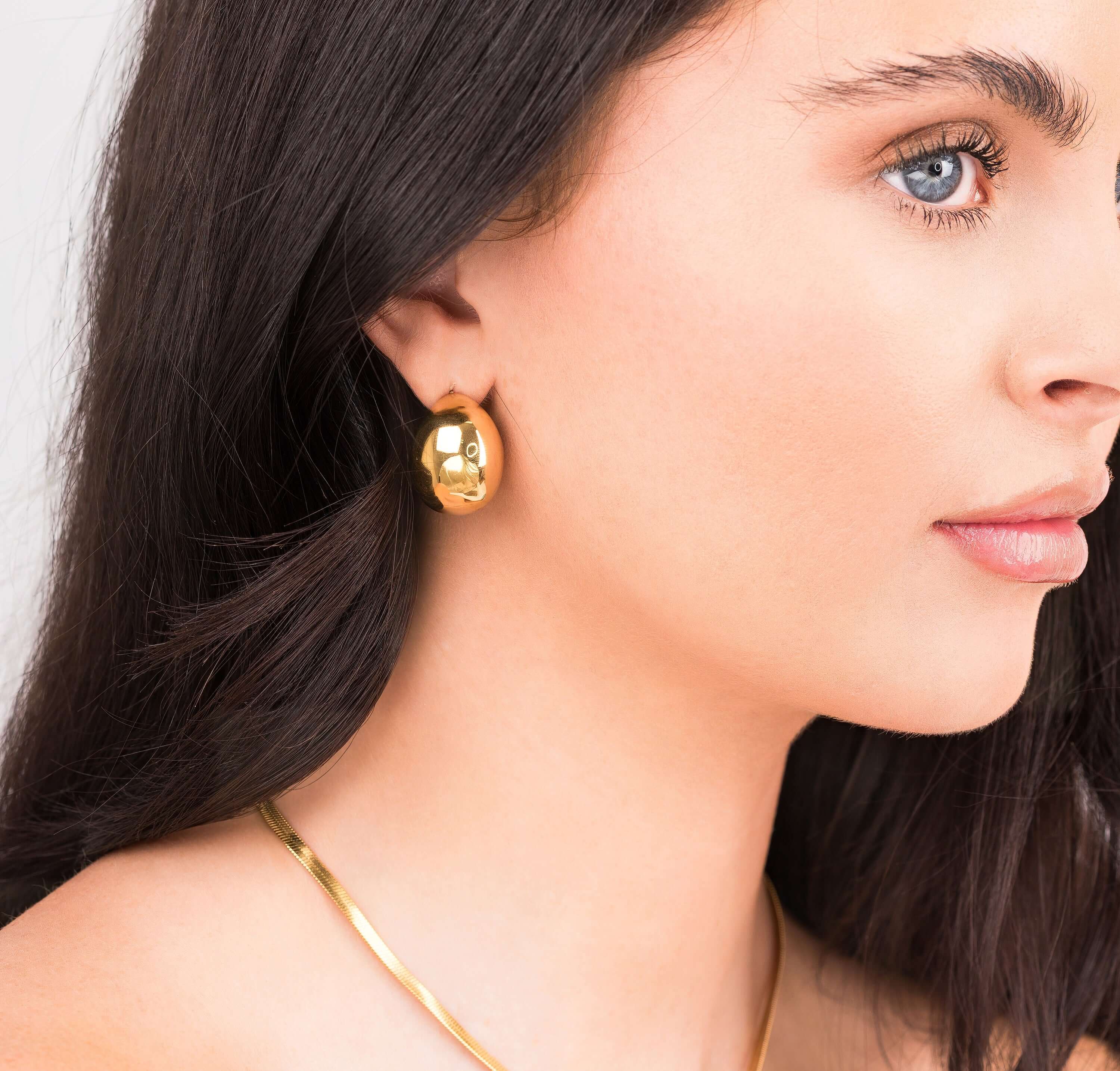Sana Gold Sculpted Dome Earrings worn by a model, showcasing their polished gold finish and elegant design.