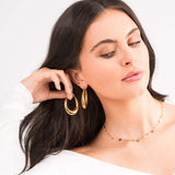 Model wearing Elise Gold Teardrop Hoop Earrings by ARIIRA, showcasing their elegant design and high-shine finish.