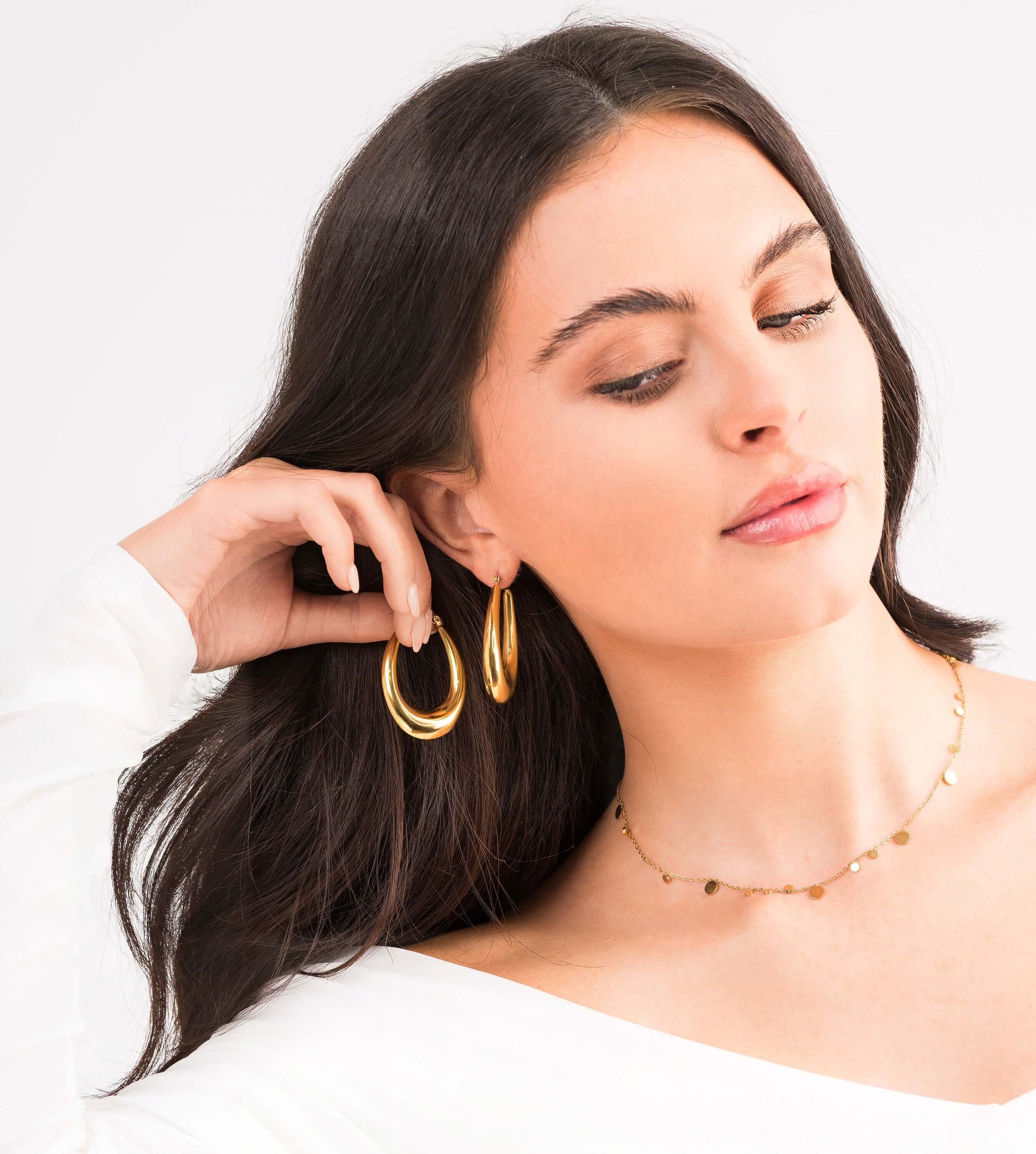 Model wearing Elise Gold Teardrop Hoop Earrings by ARIIRA, showcasing their elegant design and high-shine finish.