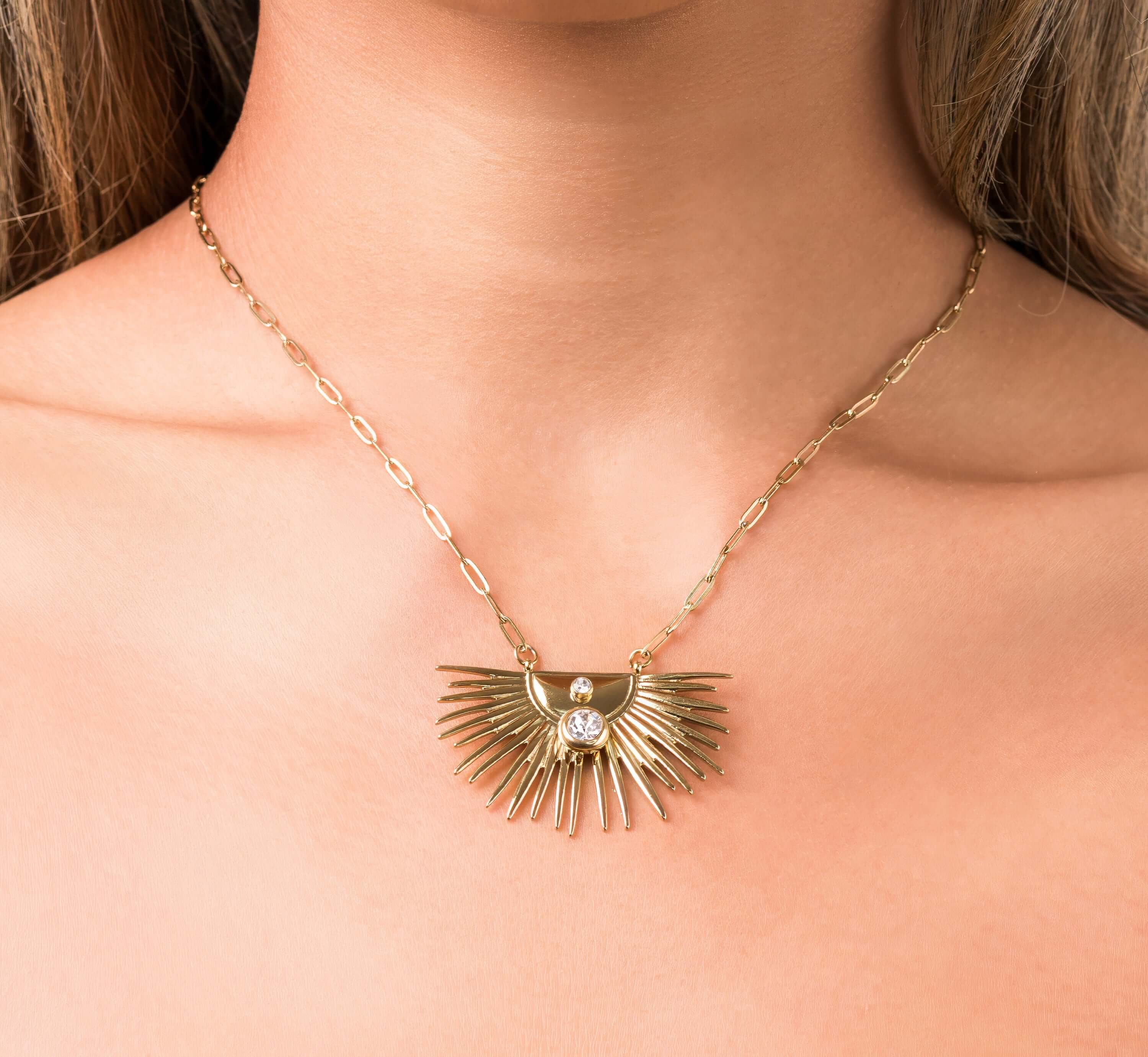 Elara Radiant Sunburst Pendant Necklace with crystal detail, symbolizing clarity and power, worn close to the heart.