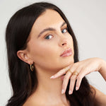 Close-up of a model showcasing Ayla Twist Band Ring and gold hoop earrings, emphasizing elegant jewelry styling.
