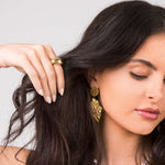 Close-up of a woman wearing the Noura Dome Band Ring and statement earrings, showcasing a stylish jewelry look.