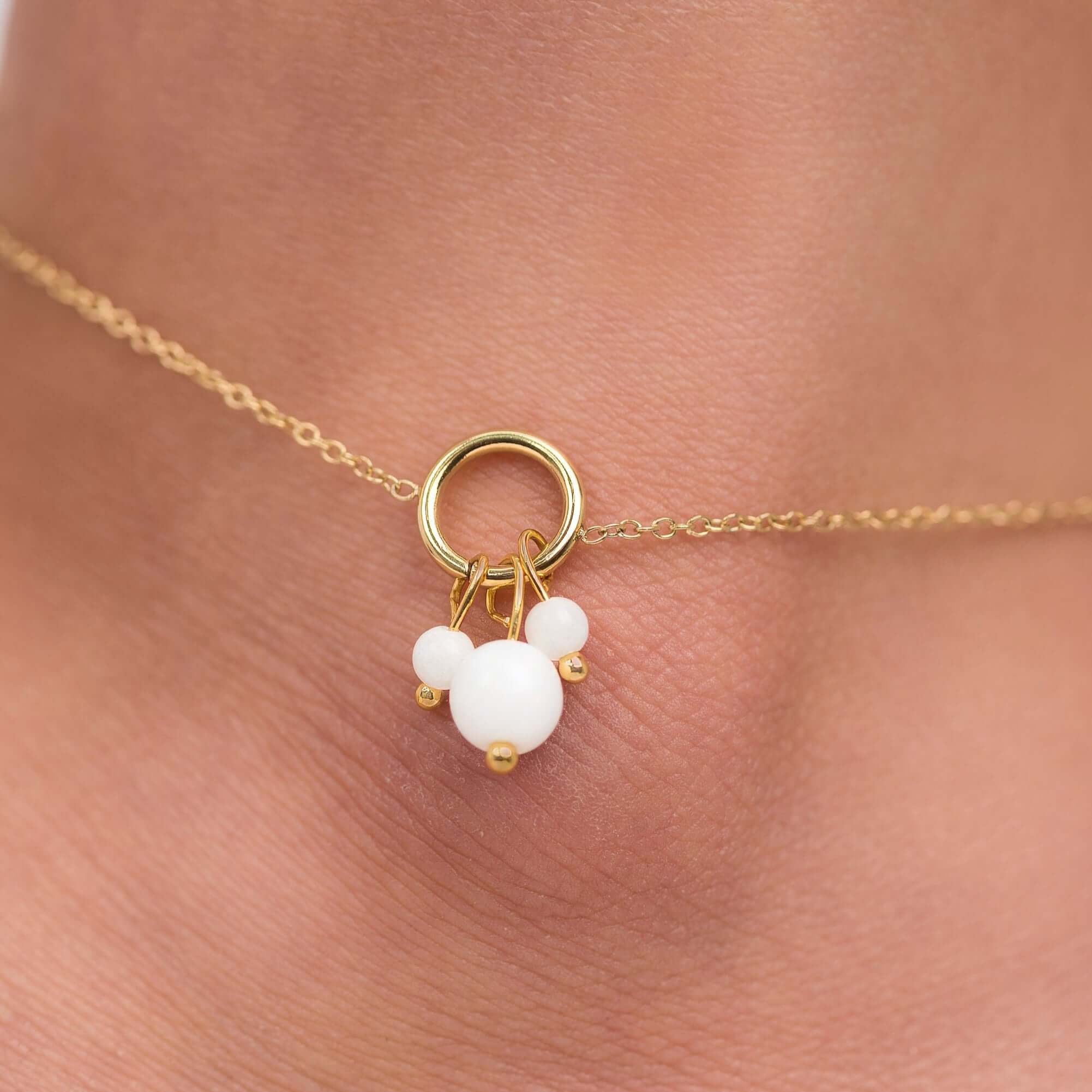 Close-up of a delicate gold-plated anklet featuring pearl-like charms, showcasing elegance and femininity.