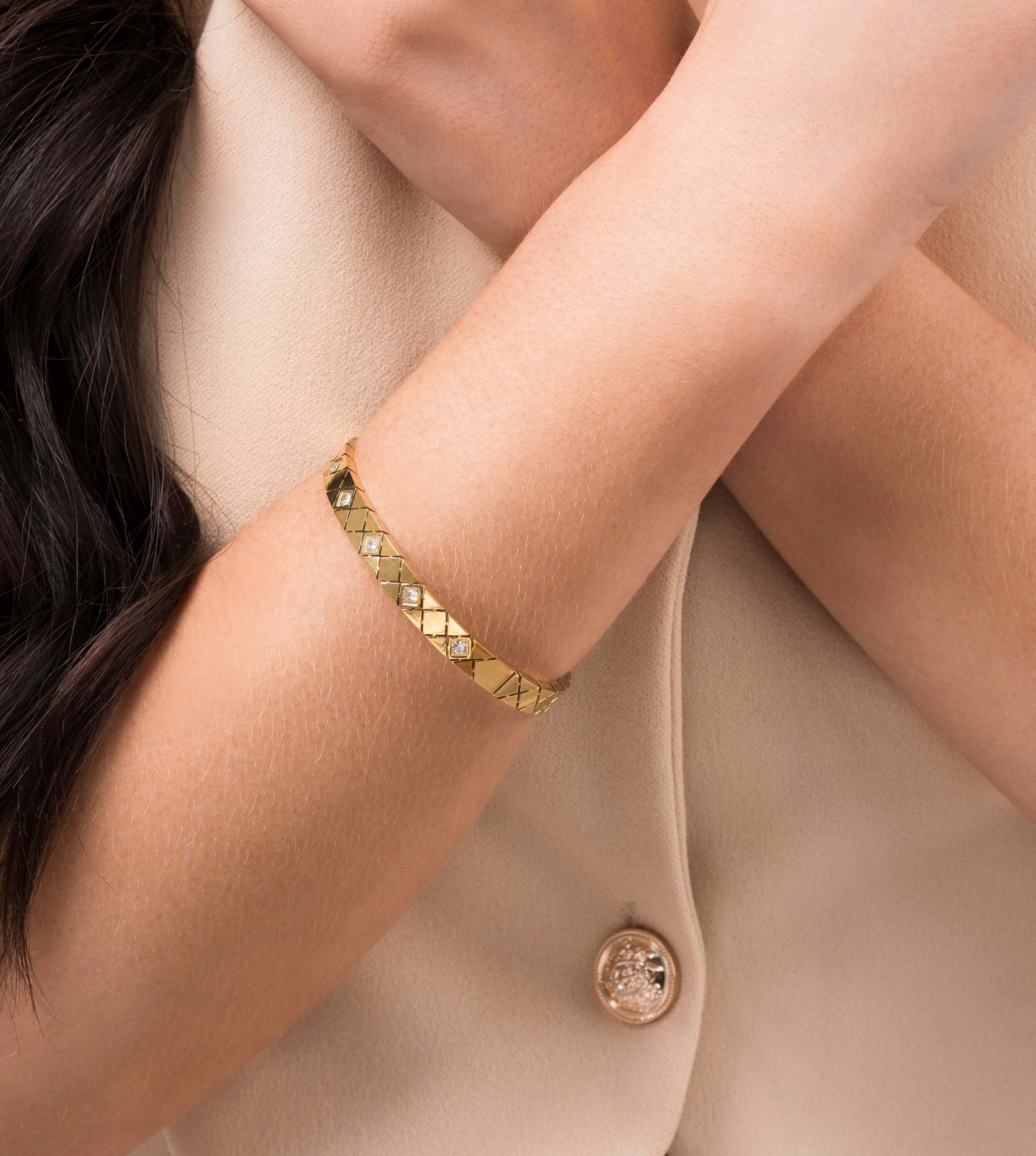 Ameera Lattice Engraved Gold Bangle Bracelet worn on a woman's wrist, showcasing its elegant crisscross design.