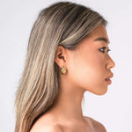 Profile view of a model wearing ARIIRA textured curve hoop earrings, showcasing elegance and modern design.