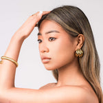 Model showcasing Yara Ribbed Dome Statement Earrings with a high-polish gold finish and a sleek hairstyle.
