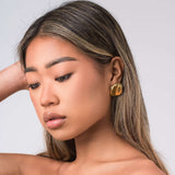 Close-up of a woman wearing ARIIRA Lara Organic Drop Studs earrings, showcasing their modern design and polished glow.