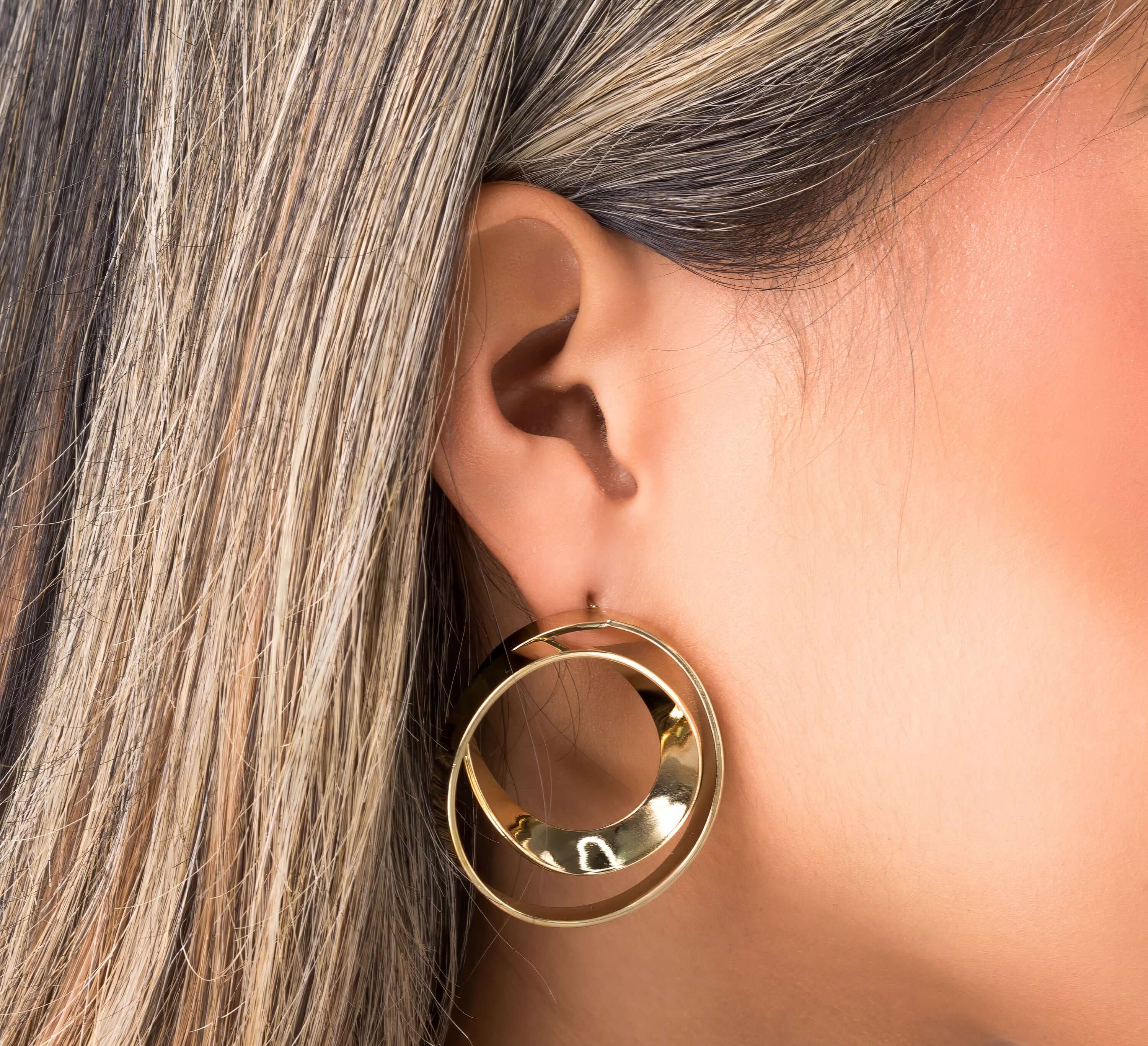 Close-up of a model wearing ARIIRA Noor Double Hoop Statement Earrings in polished gold, showcasing their elegant design.