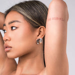 A model showcasing ARIIRA's Lara Organic Drop Studs earrings, highlighting their modern design and polished finish.