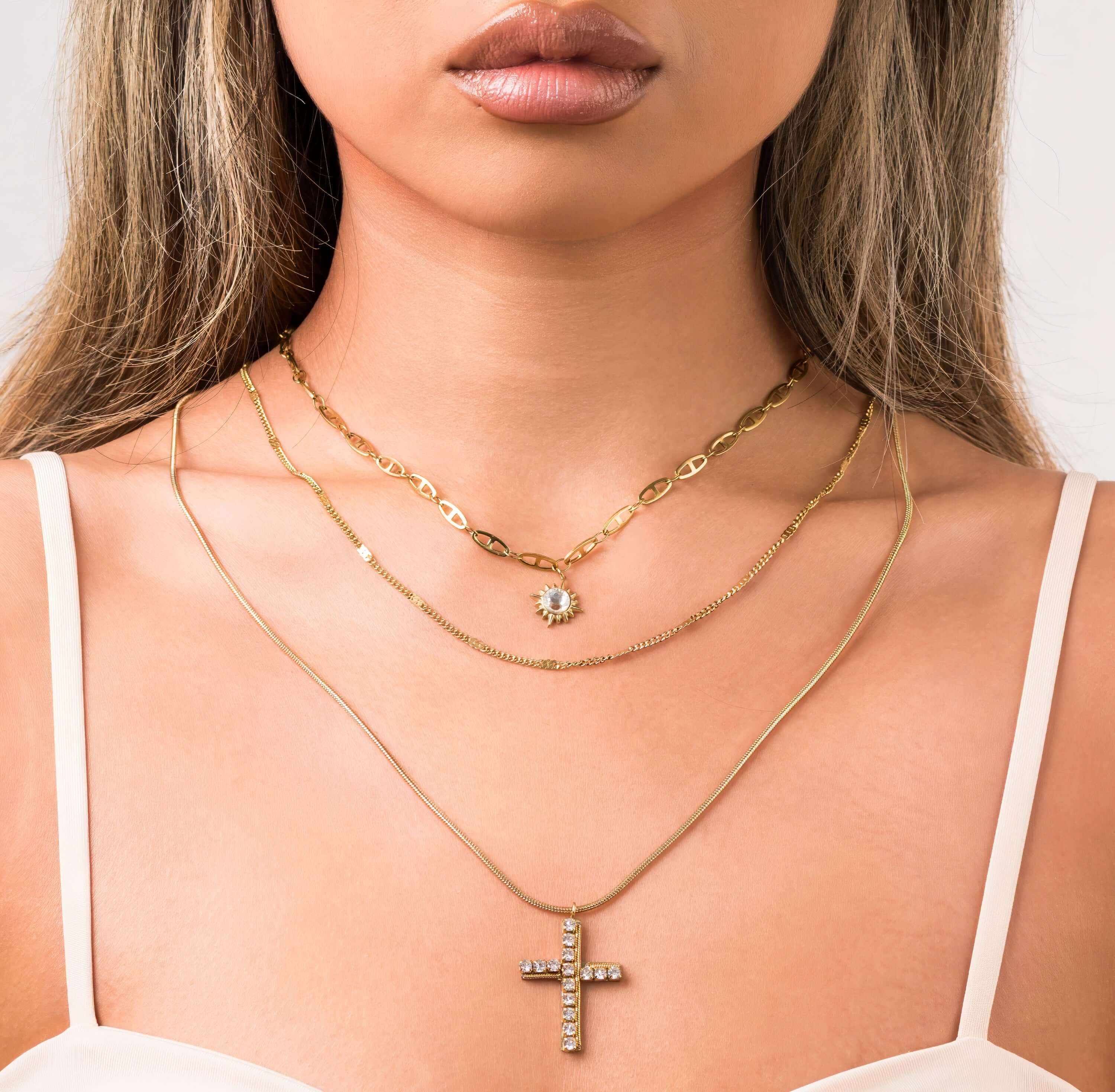 Nour Layered Sun & Cross Necklace Set from ARIIRA featuring three unique chains and elegant charms.
