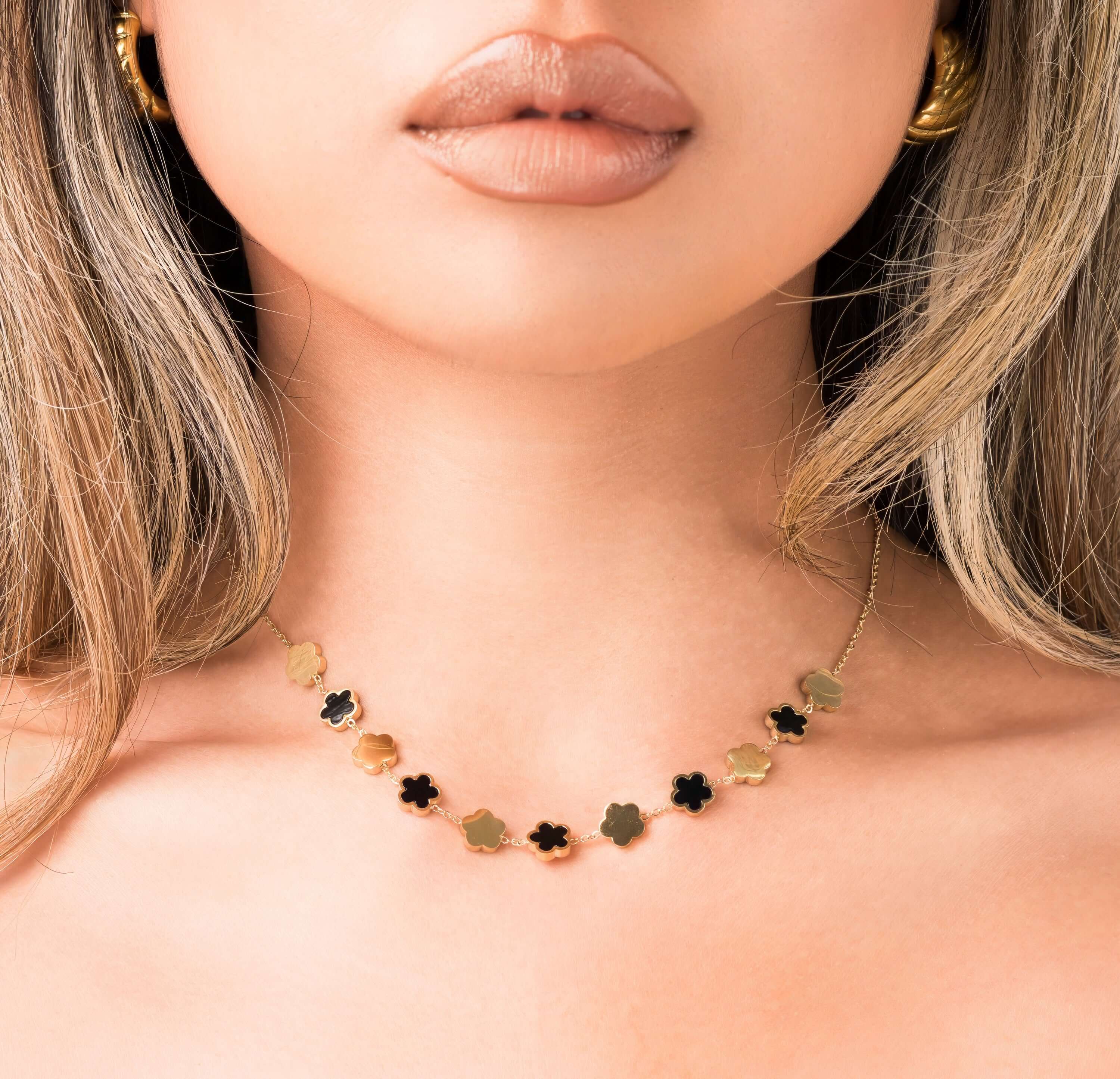 Woman wearing ARIIRA Soraya Enamel Clover Link Necklace with smooth enamel and gold-tone clover links.