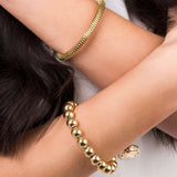 Elegant ARIIRA Divina polished beaded gold bangle alongside a textured gold bracelet on a model's wrist.